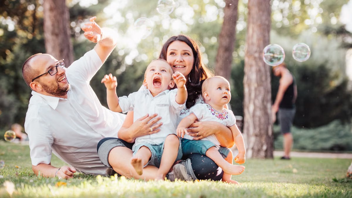 Joyful family enjoying a sunny day in the park while playing with bubbles.