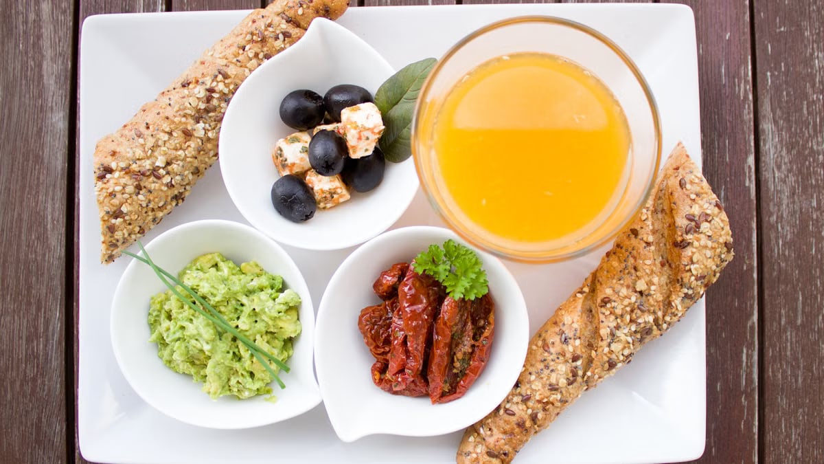 A delicious and nutritious breakfast featuring juice, bread, and fresh toppings on a white plate.